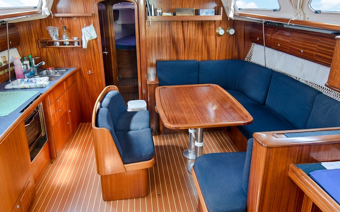 Sailboat interior with dining area and kitchen, La Maddalena Archipelago excursion.