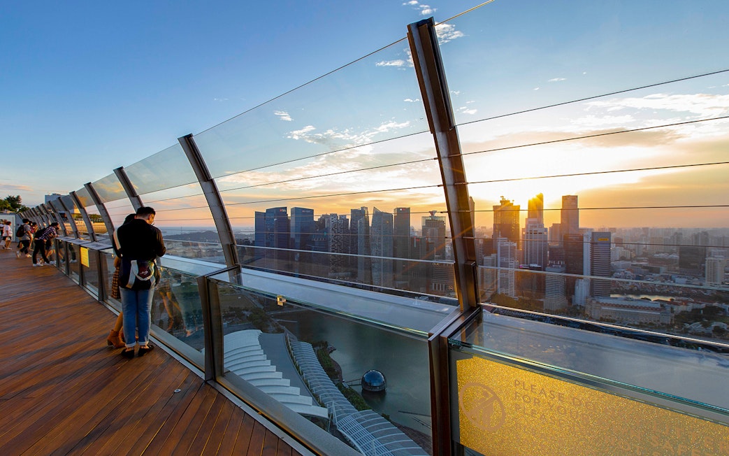 Skyline view from Marina Bay Sands SkyPark at sunset, overlooking Gardens by the Bay, Singapore.