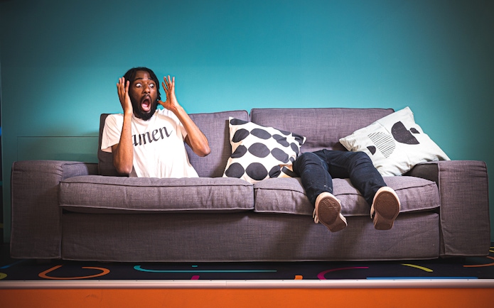 Person on a tilted couch at Paradox Museum, Stockholm, appearing surprised.