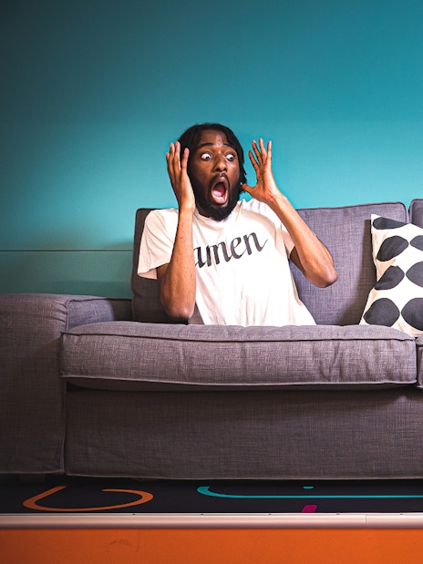 Person on a tilted couch at Paradox Museum, Stockholm, appearing surprised.