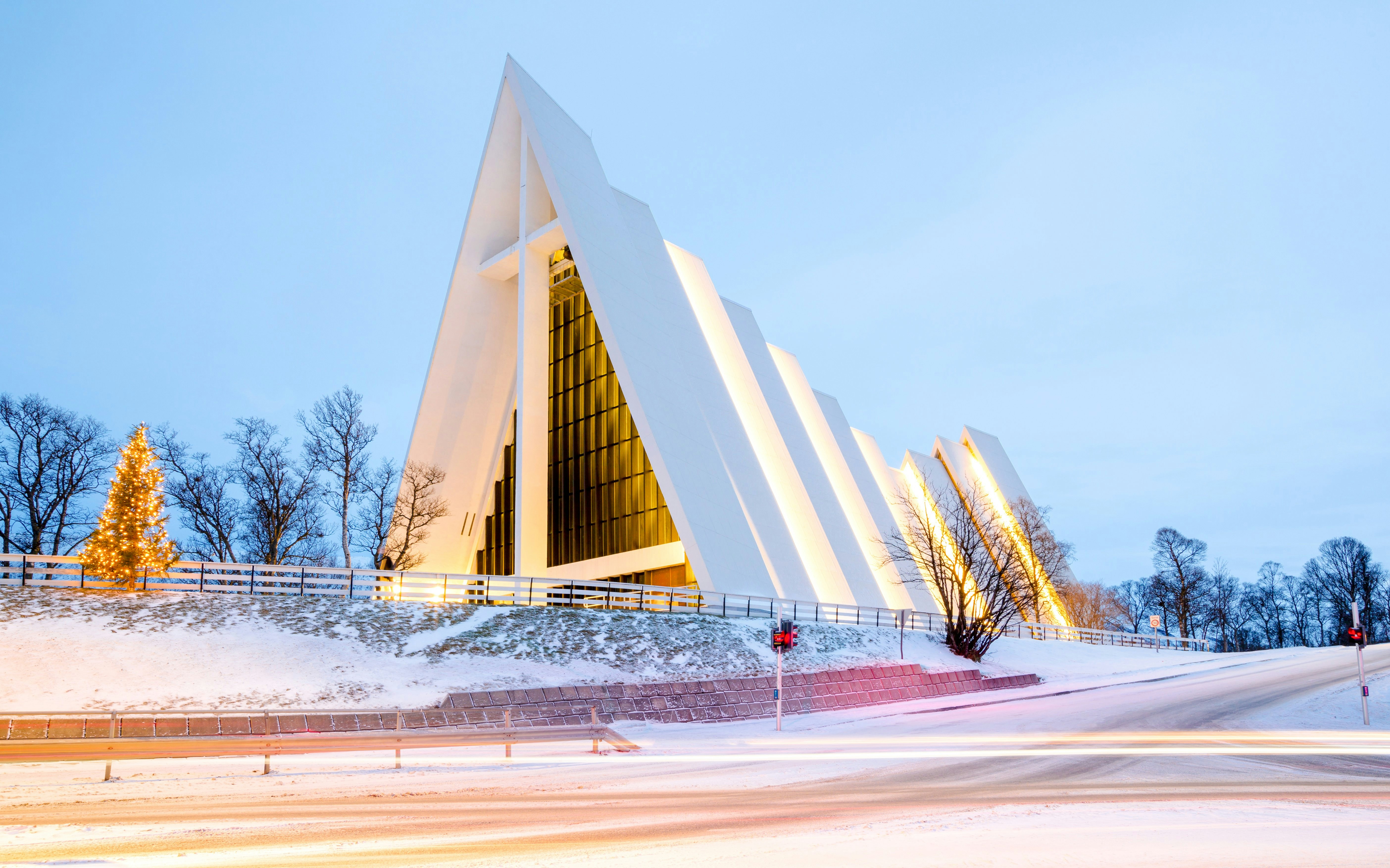 Arctic Cathedral in Tromsø illuminated at dusk with snow-covered surroundings.