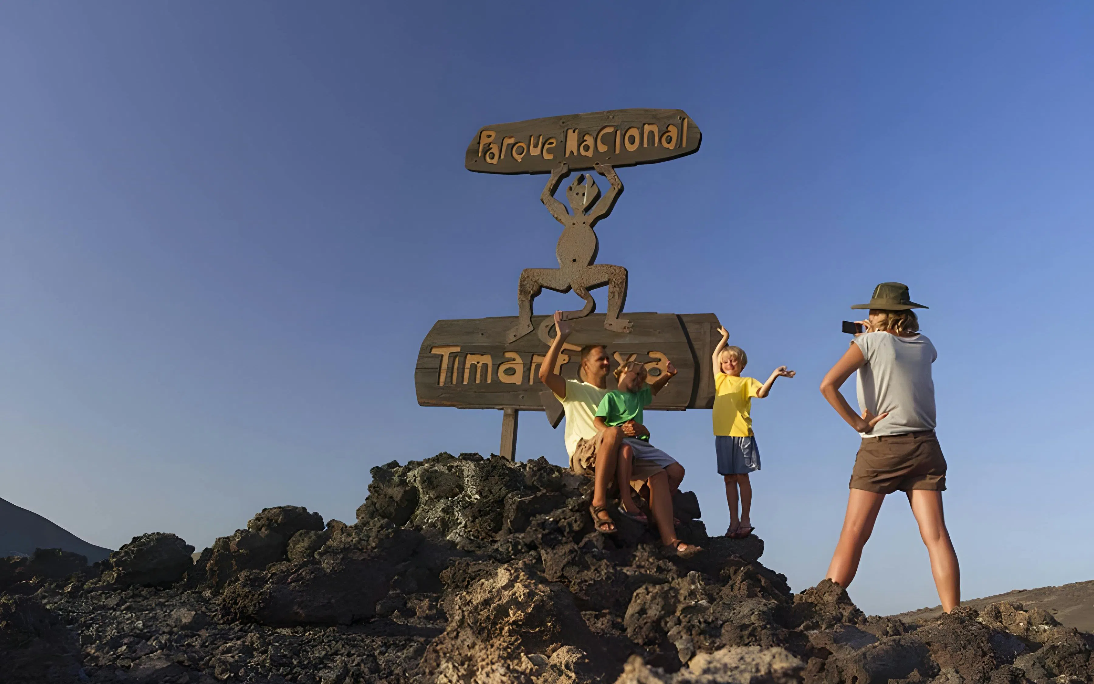 Tourists posing in front of Timanfaya National Park sign in Lanzarote.