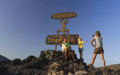 Tourists posing in front of Timanfaya National Park sign in Lanzarote.