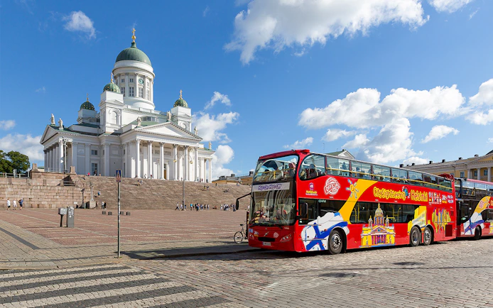 Hop-on hop-off bus in front of Helsinki Cathedral on a sunny day.