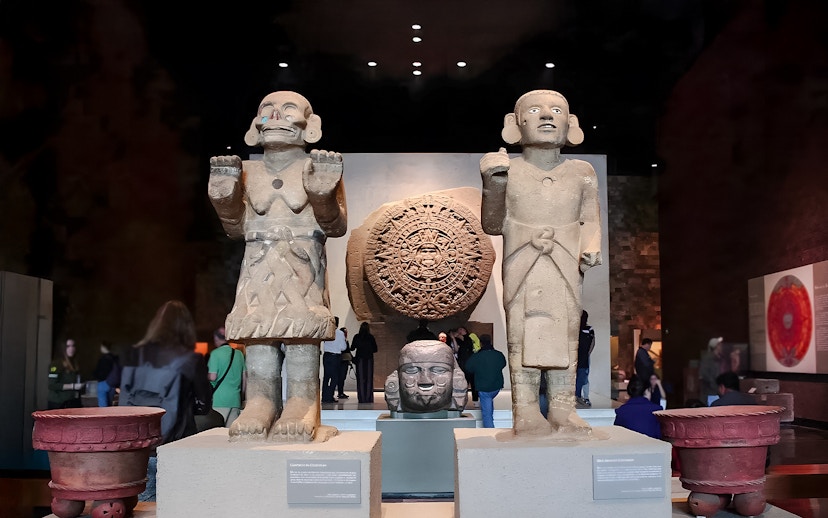 Visitors viewing ancient sculptures and the Aztec calendar stone at the Anthropology Museum, Mexico City.