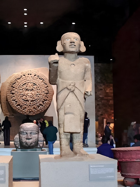 Visitors viewing ancient sculptures and the Aztec calendar stone at the Anthropology Museum, Mexico City.