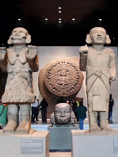 Visitors viewing ancient sculptures and the Aztec calendar stone at the Anthropology Museum, Mexico City.