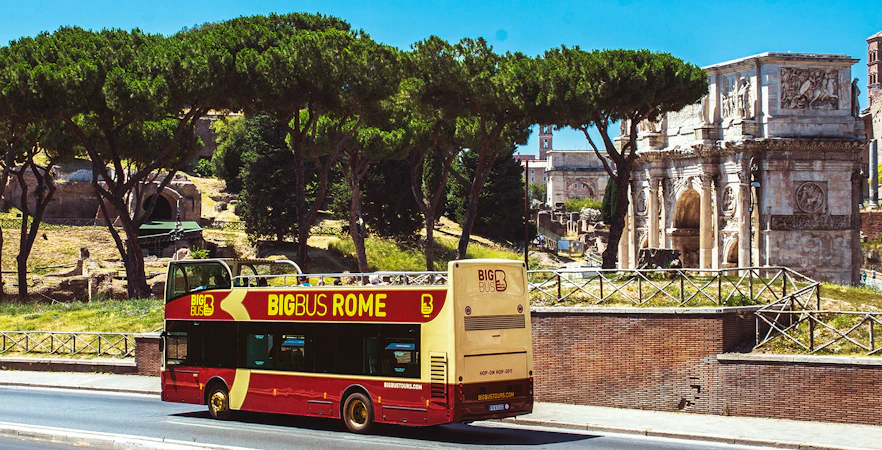 Big Bus Rome tour passing by the Arch of Constantine in Rome, Italy.