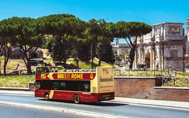 Big Bus Rome tour passing by the Arch of Constantine in Rome, Italy.