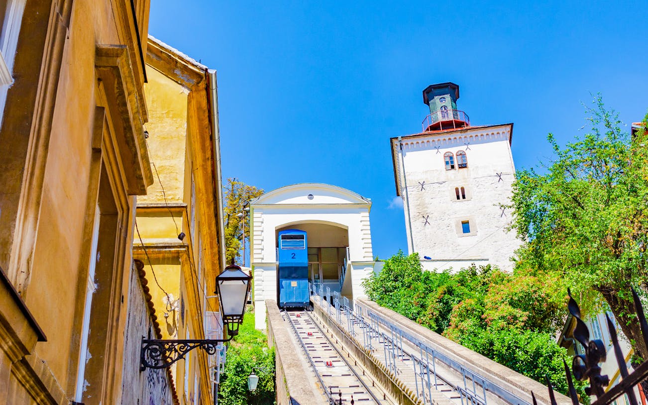 Funicular ascending in Zagreb with historic buildings and Lotrščak Tower.