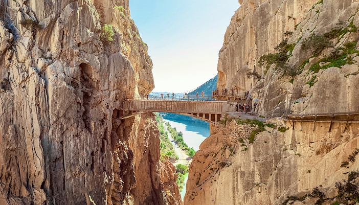 Hikers crossing a narrow bridge along the Caminito del Rey trail in Málaga, Spain.
