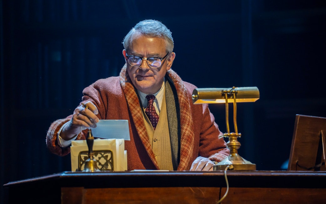 Stage scene from Shadowlands in Westend, actor at desk with lamp and papers.