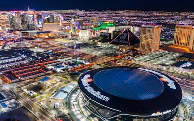 Aerial view of Allegiant Stadium and Las Vegas Strip at night during helicopter tour.