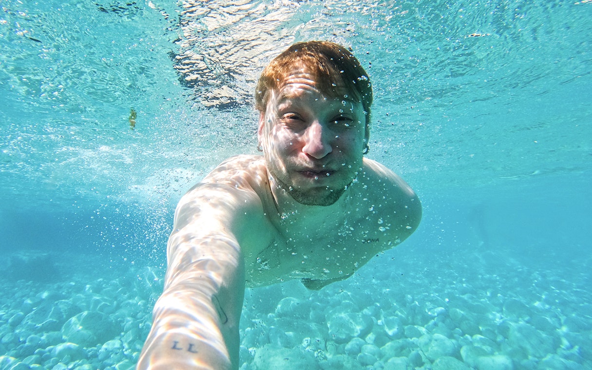 Underwater view of a person swimming in clear Capri waters during a kayak tour.