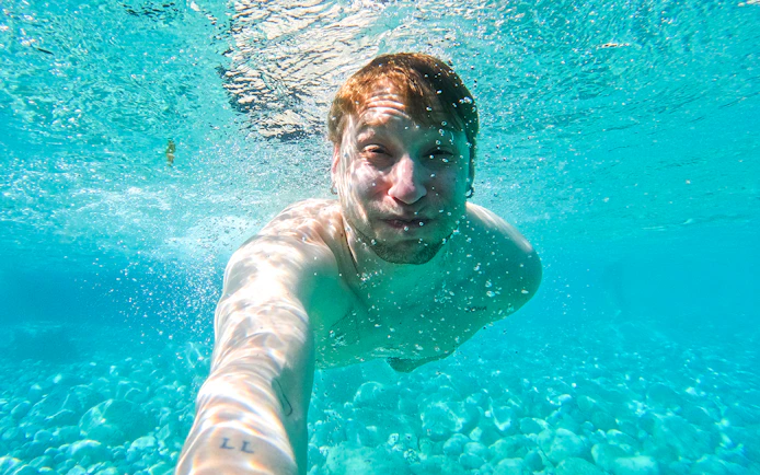 Underwater view of a person swimming in clear Capri waters during a kayak tour.