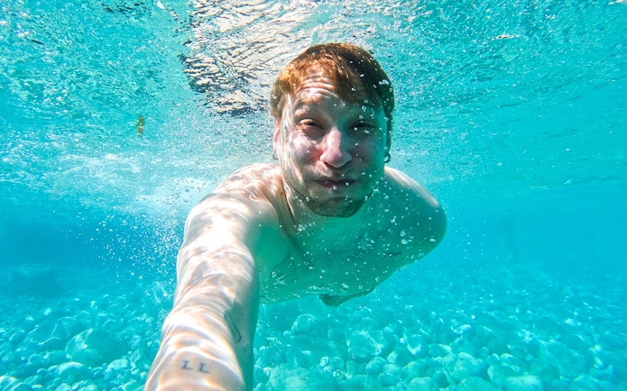 Underwater view of a person swimming in clear Capri waters during a kayak tour.