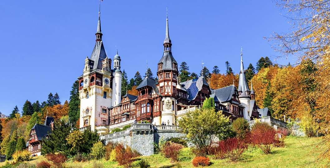 Peles Castle in Sinaia, Romania, surrounded by autumn foliage.