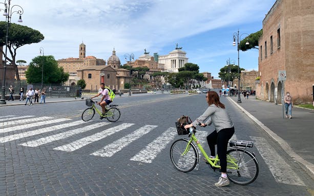 Cyclists on Via dei Fori Imperiali with Altare della Patria in Rome, Italy.