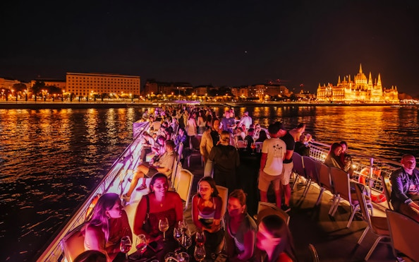 Cruise guests enjoying a night view of Budapest Parliament from the Danube River.