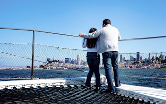 Guests on a sailing cruise enjoying San Francisco Bay skyline views.