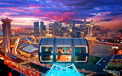 Couple in a cabin on the Singapore Flyer with city skyline at sunset.