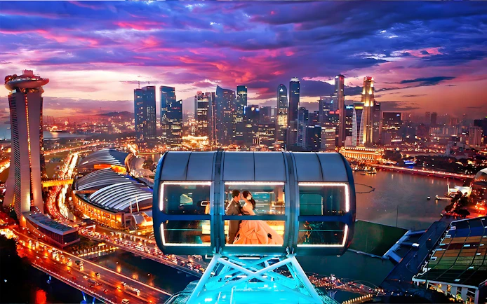 Couple in a cabin on the Singapore Flyer with city skyline at sunset.