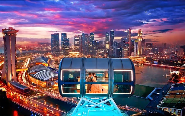 Couple in a cabin on the Singapore Flyer with city skyline at sunset.