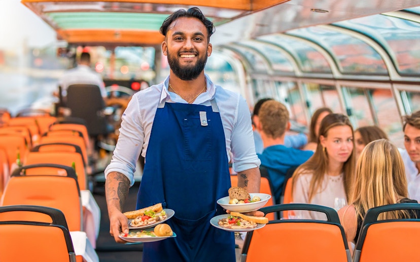 Service staff on a dinner cruise serving meals to guests on a boat.