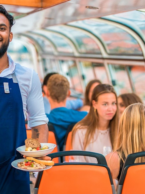 Service staff on a dinner cruise serving meals to guests on a boat.