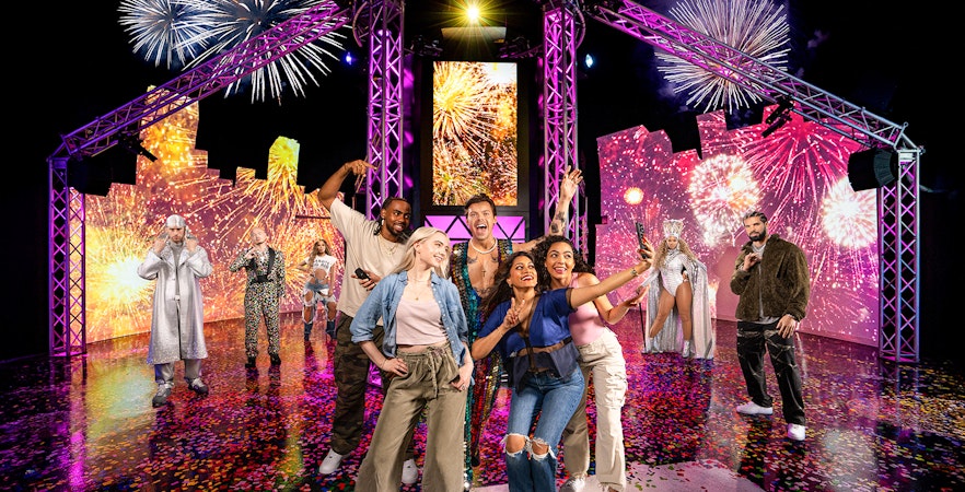 Guests posing with wax figures of musical artists at Madame Tussauds, New York.