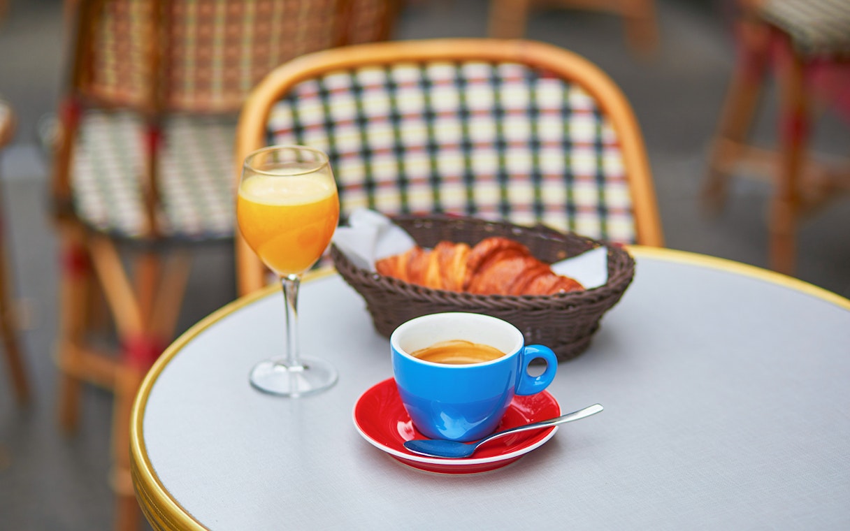Coffee, orange juice, and croissants on a table during a Seine River cruise breakfast in Paris.