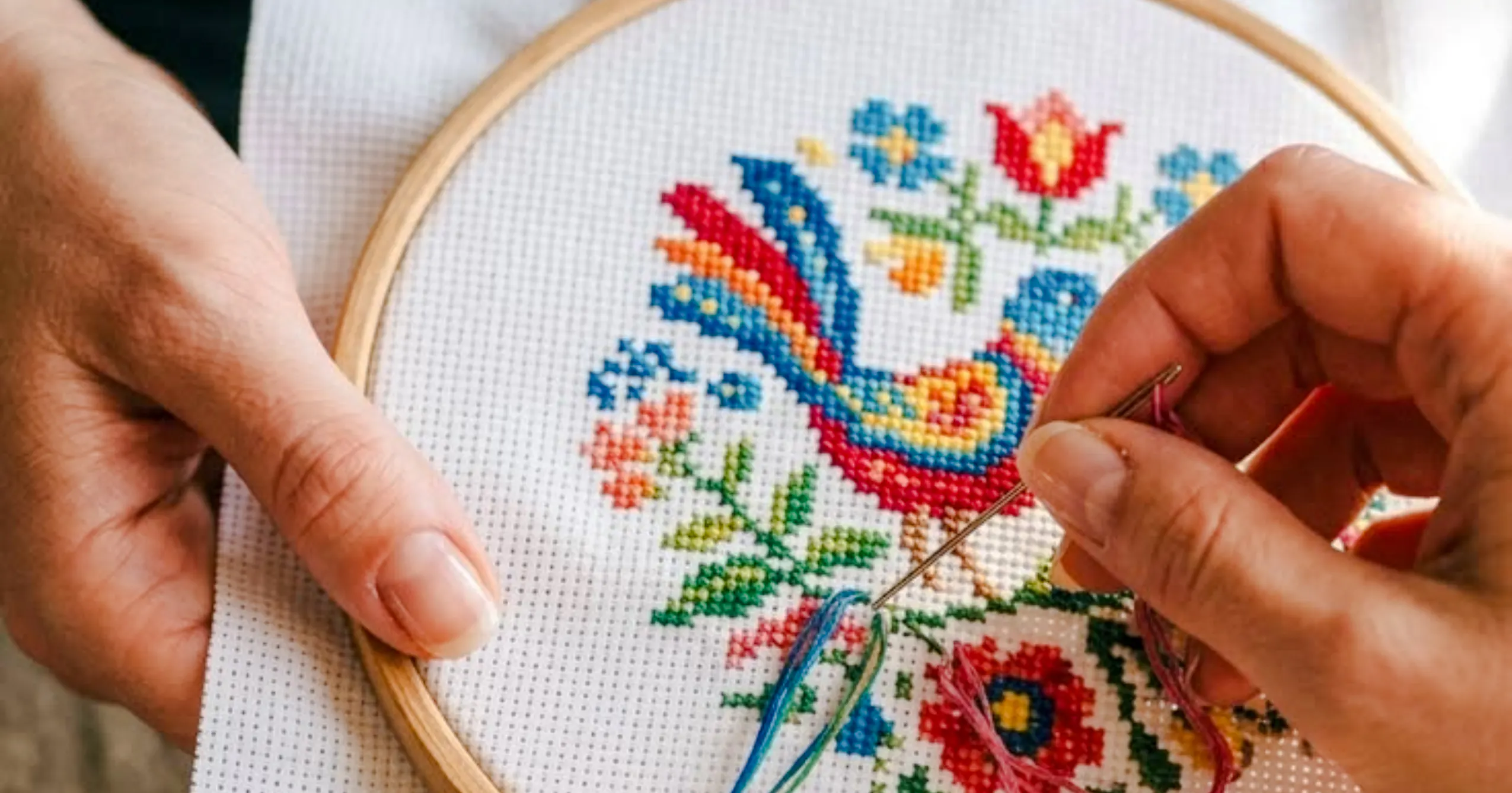 Embroidery of colorful bird and flowers in upcycled textile workshop, Essaouira.