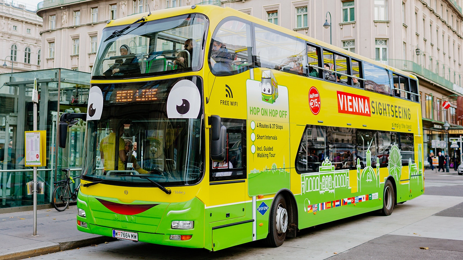 Vienna cityscape with hop-on hop-off tour bus near historic buildings and city.