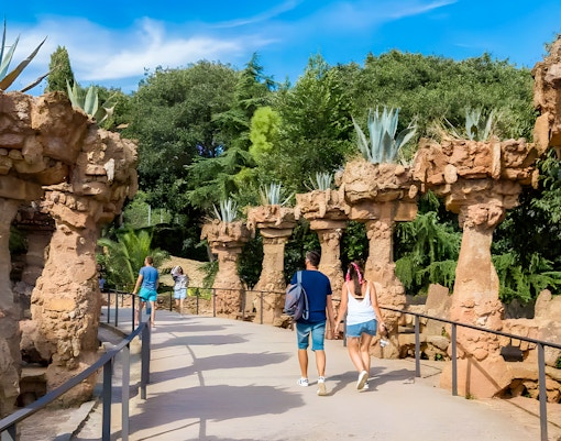 Park Güell garden pathway with colorful mosaic benches, Barcelona, Spain.