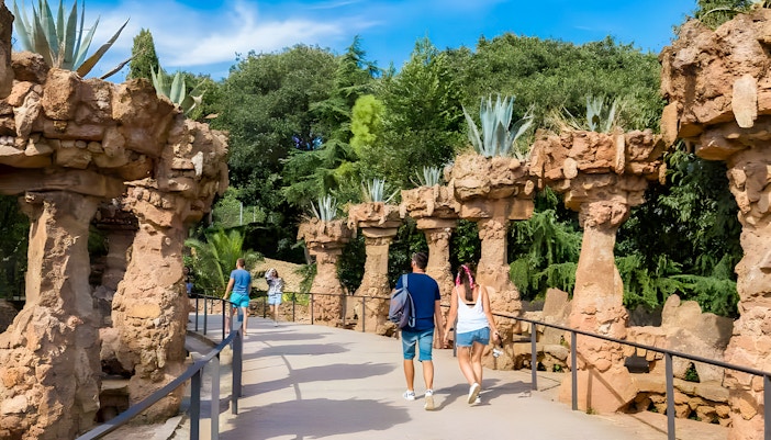 Park Güell garden pathway with colorful mosaic benches, Barcelona, Spain.