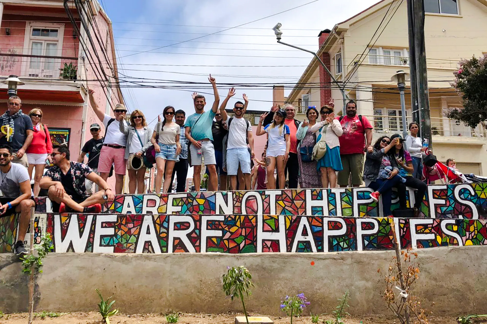 Group of tourists in Valparaíso with colorful mosaic wall reading "We Are Happies.