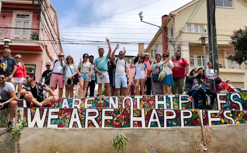 Group of tourists in Valparaíso with colorful mosaic wall reading "We Are Happies.