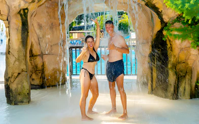 Couple enjoying waterfall at Aquopolis Torrevieja water park.