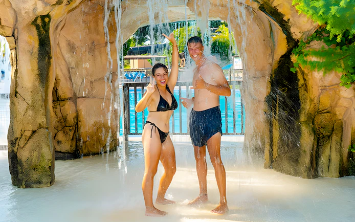 Couple enjoying waterfall at Aquopolis Torrevieja water park.