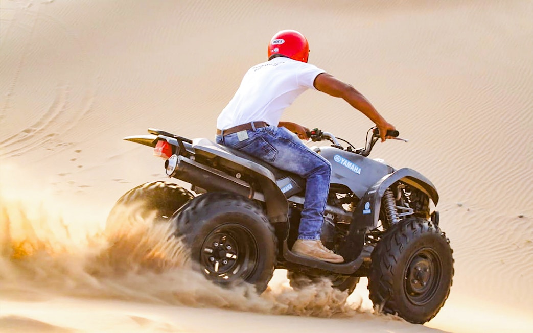 Quad bike rider navigating sand dunes in Abu Dhabi.