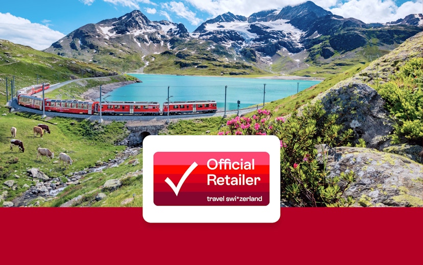 Train traveling through Swiss Alps near a turquoise lake with mountains in the background.
