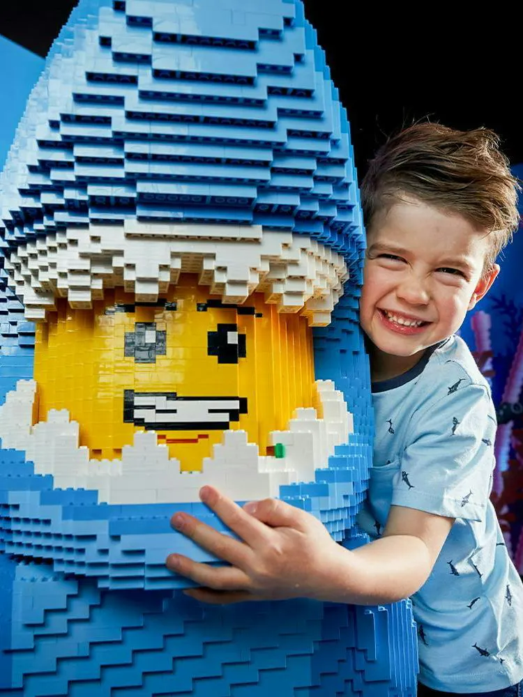 Child embracing LEGO shark figure at LEGOLAND Discovery Centre.
