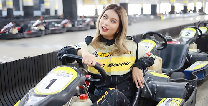 Woman sitting in a go-kart at an indoor track in Bangkok.