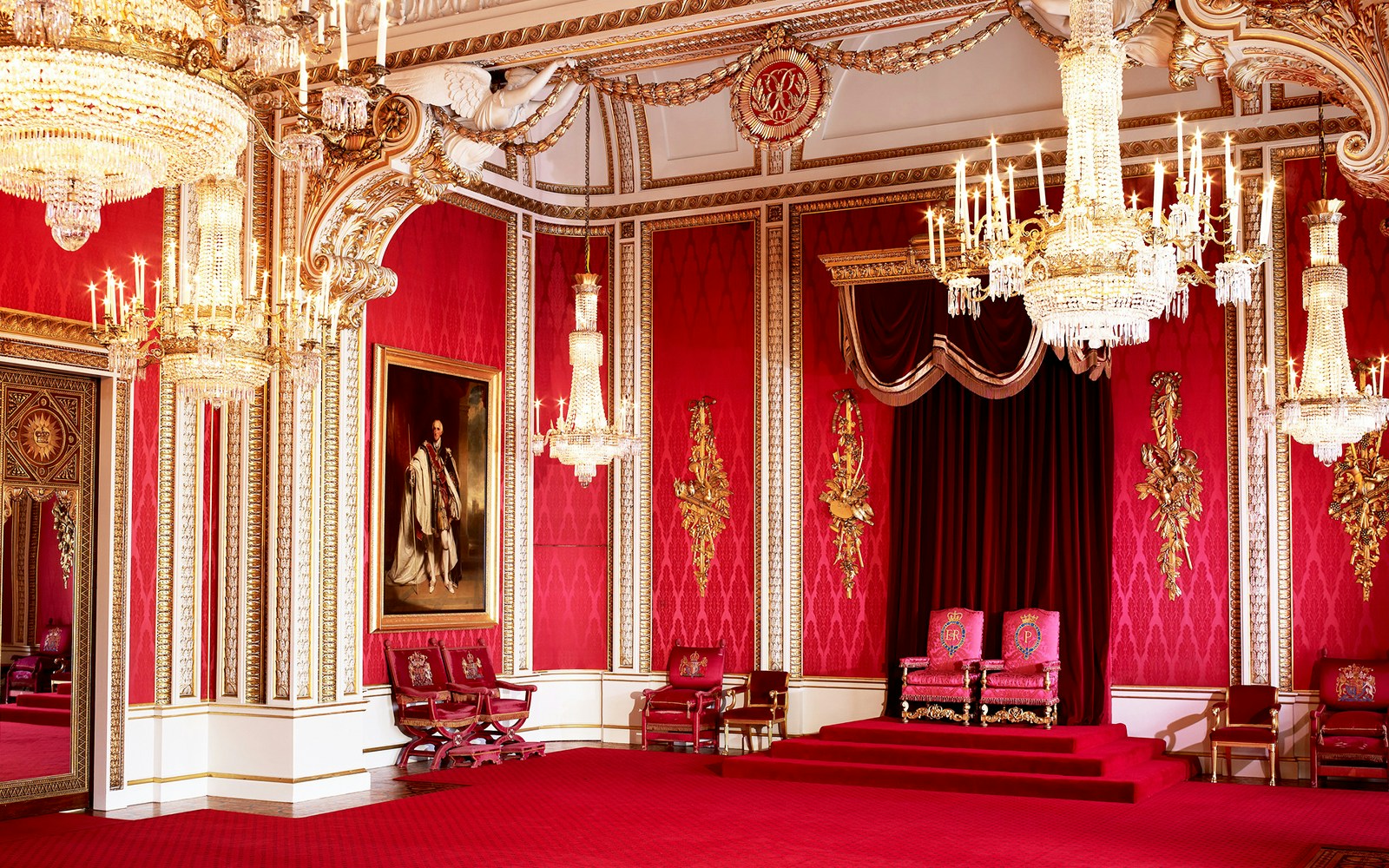 Buckingham Palace state room interior with chandeliers and ornate red decor.