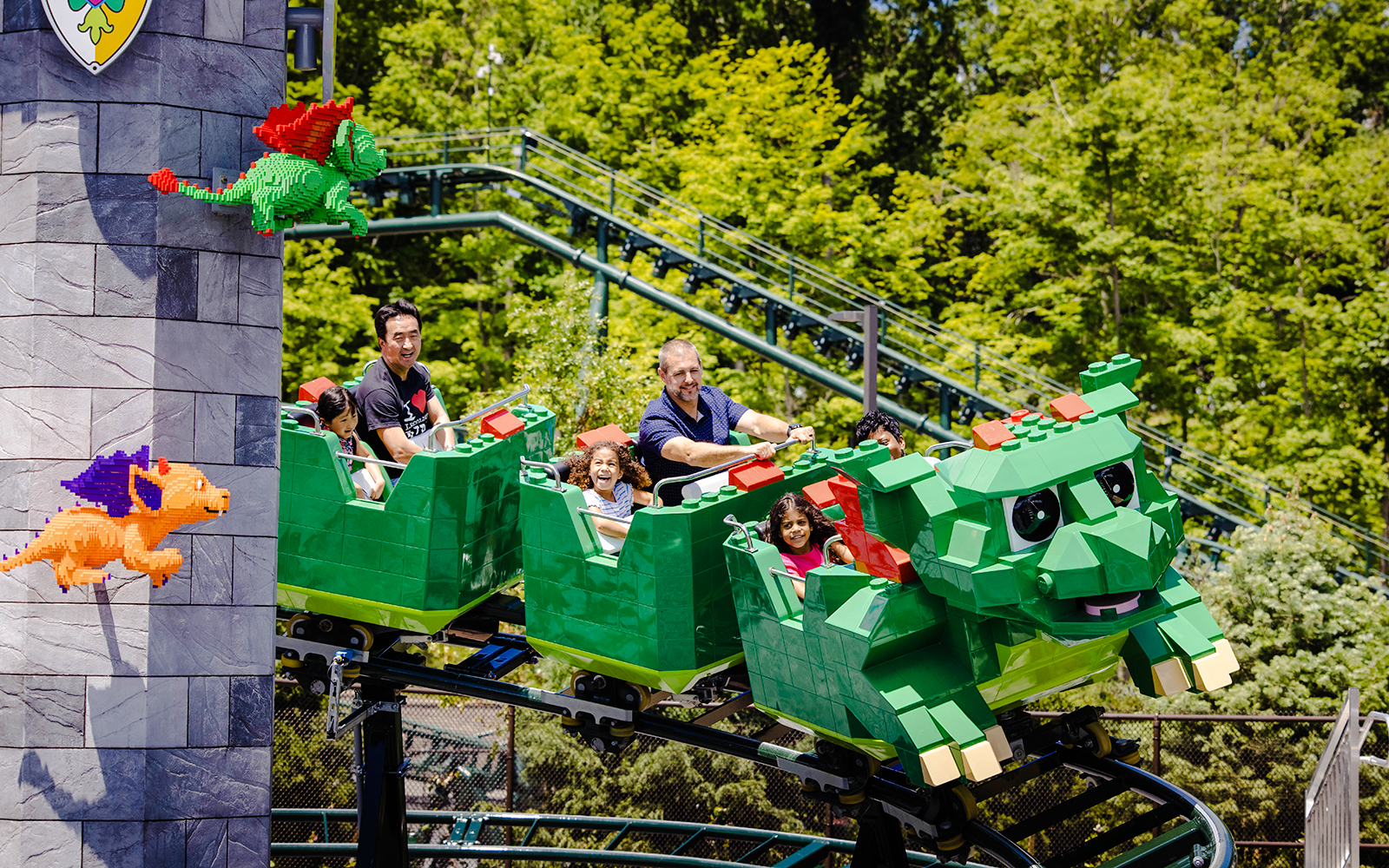 Guests enjoying a dragon-themed roller coaster at Legoland, New York.