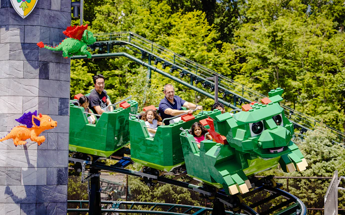 Guests enjoying a dragon-themed roller coaster at Legoland, New York.