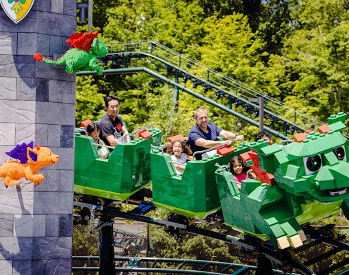 Guests enjoying a dragon-themed roller coaster at Legoland, New York.