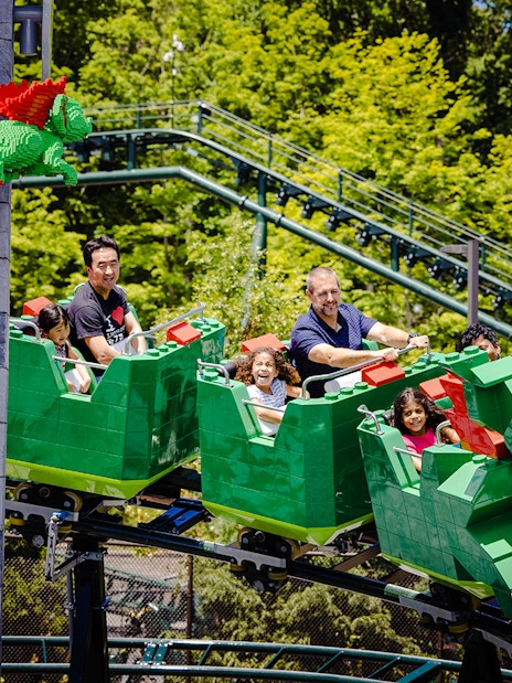 Guests enjoying a dragon-themed roller coaster at Legoland, New York.