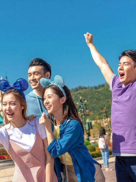 Friends taking selfie at Hong Kong Disneyland in front of castle.