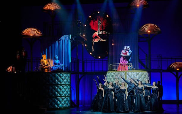 Stage scene from "Pretty Woman - El musical" with performers in elegant attire.